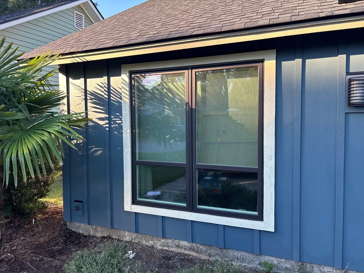 Vertical blue siding and light trim around a large front window