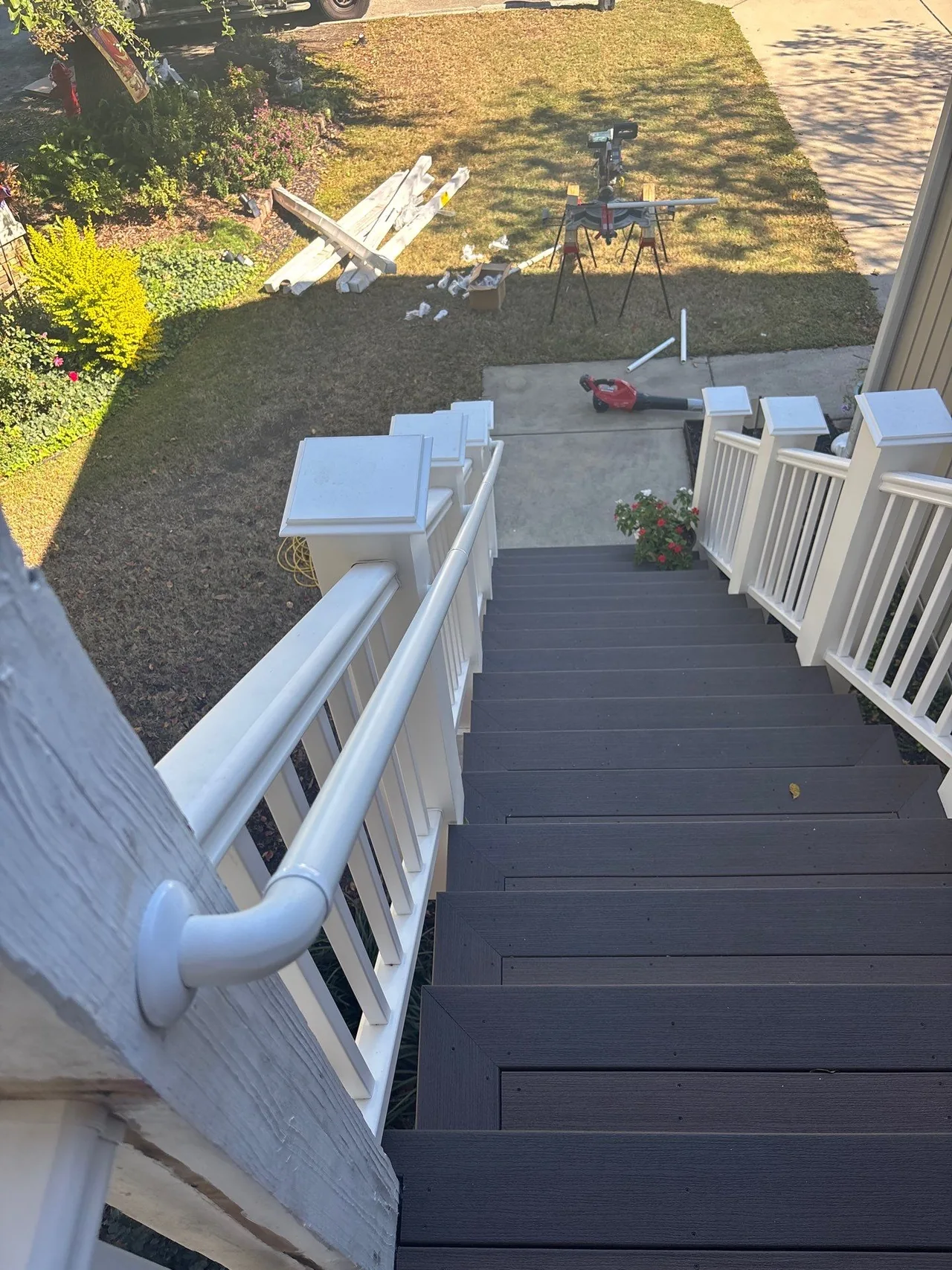 Installed composite stair treads and white rails viewed toward the yard during closeout work.
