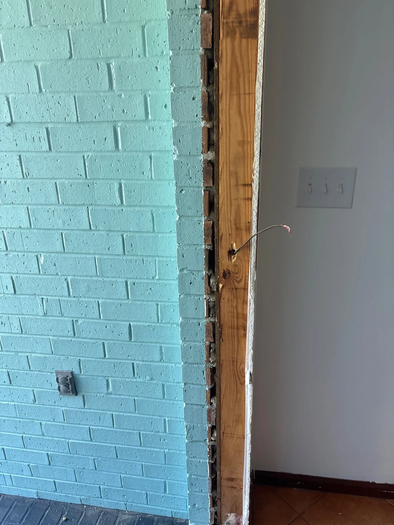 Exposed side of the front-door opening between painted brick and the interior wall during removal