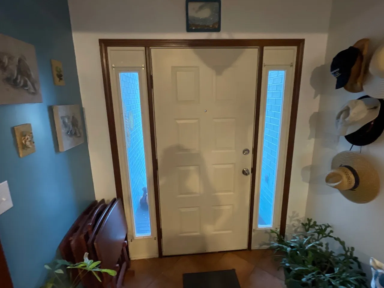 Original light-colored front door with narrow sidelights and wood-toned interior trim
