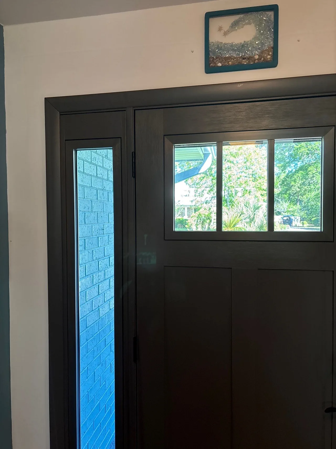 New front door with upper glass and a tall sidelight viewed from inside a Myrtle Beach entry