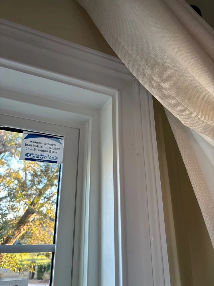 White interior window trim beside a light curtain and garden-facing glass
