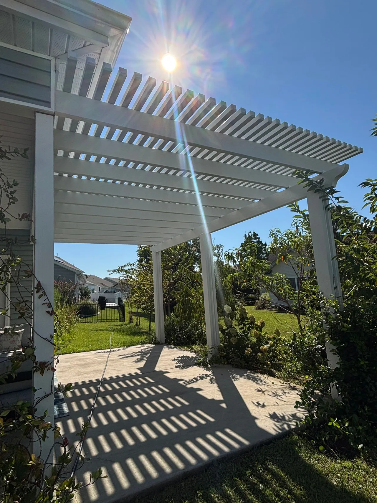 White open-slat pergola casting striped shade on a concrete patio in Surfside Beach
