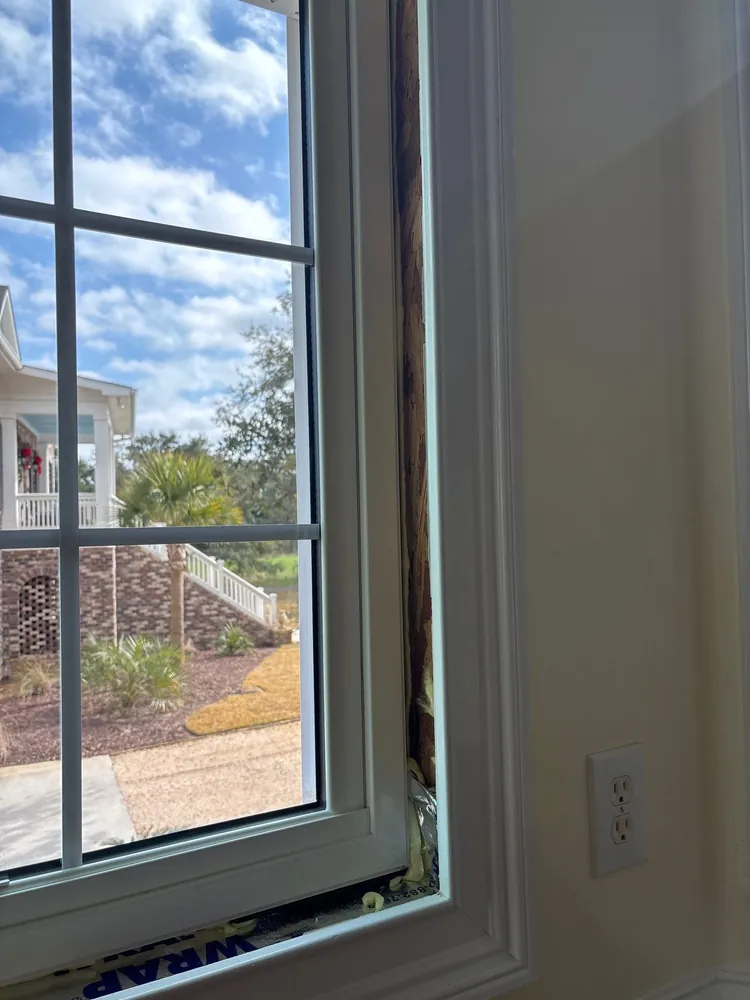 Interior close view of a replacement window with an exposed perimeter gap and foam during installation