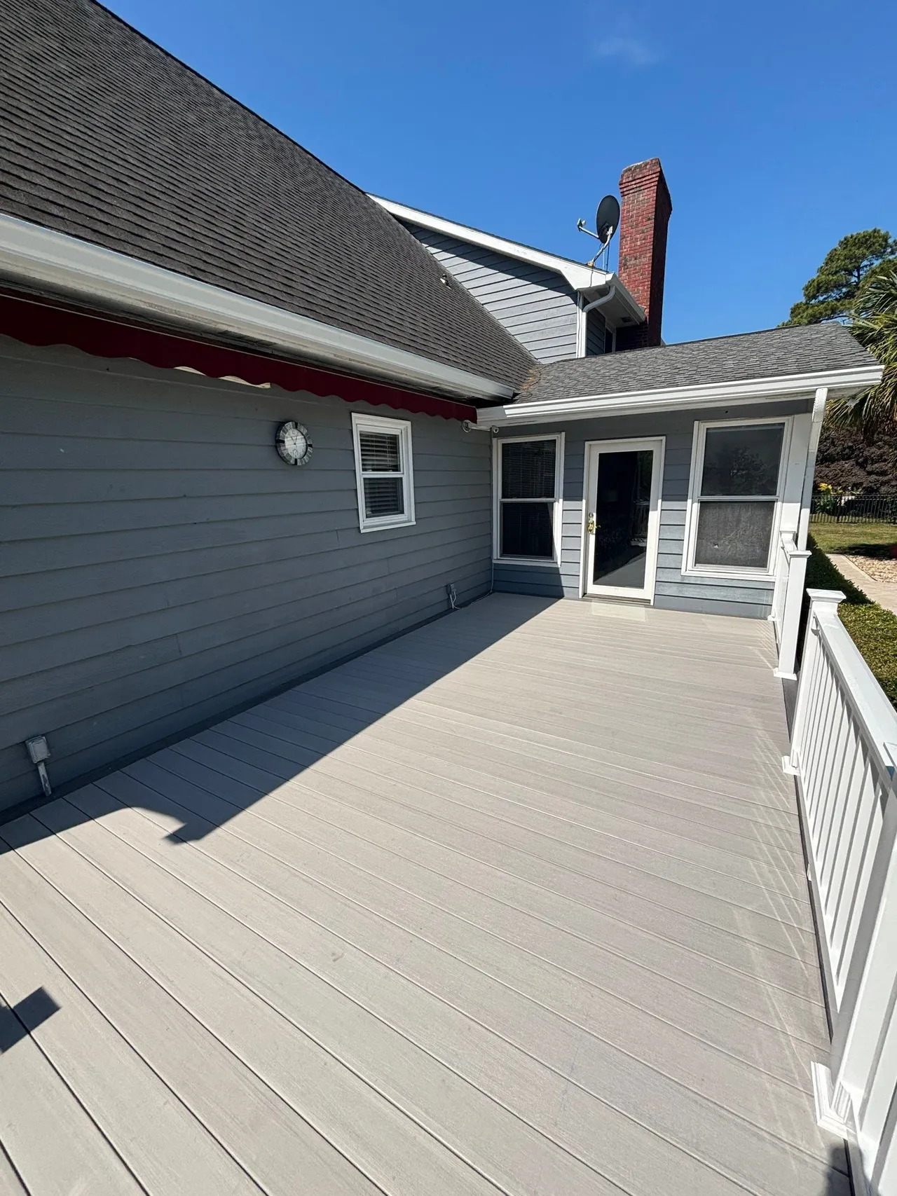 Gray Boardwalk deck boards beside the Conway home’s siding and white railing.