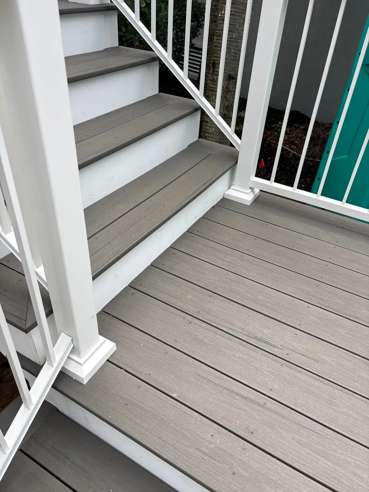 Composite landing boards meeting the next stair flight beside white posts and railing