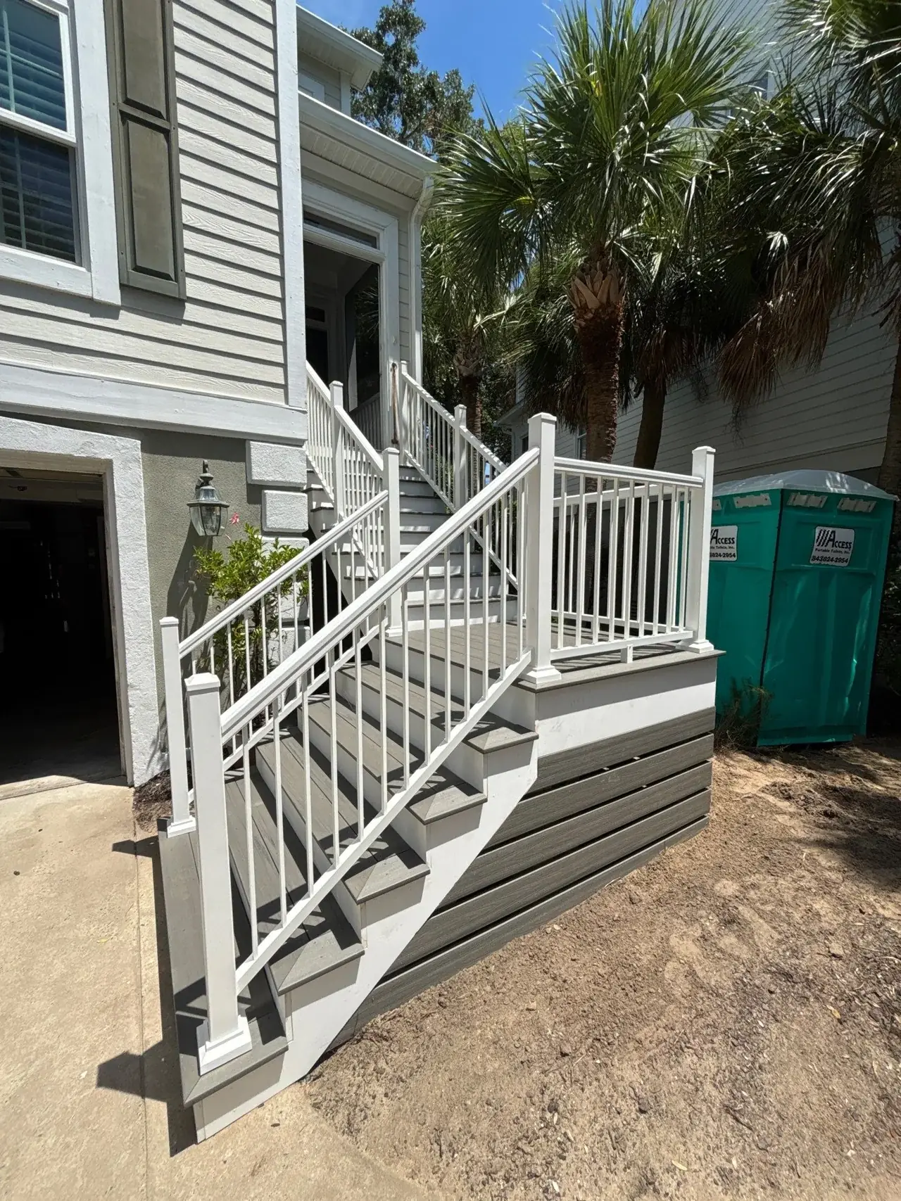 New composite stairs and landing with white railing beside a light-colored Isle of Palms home