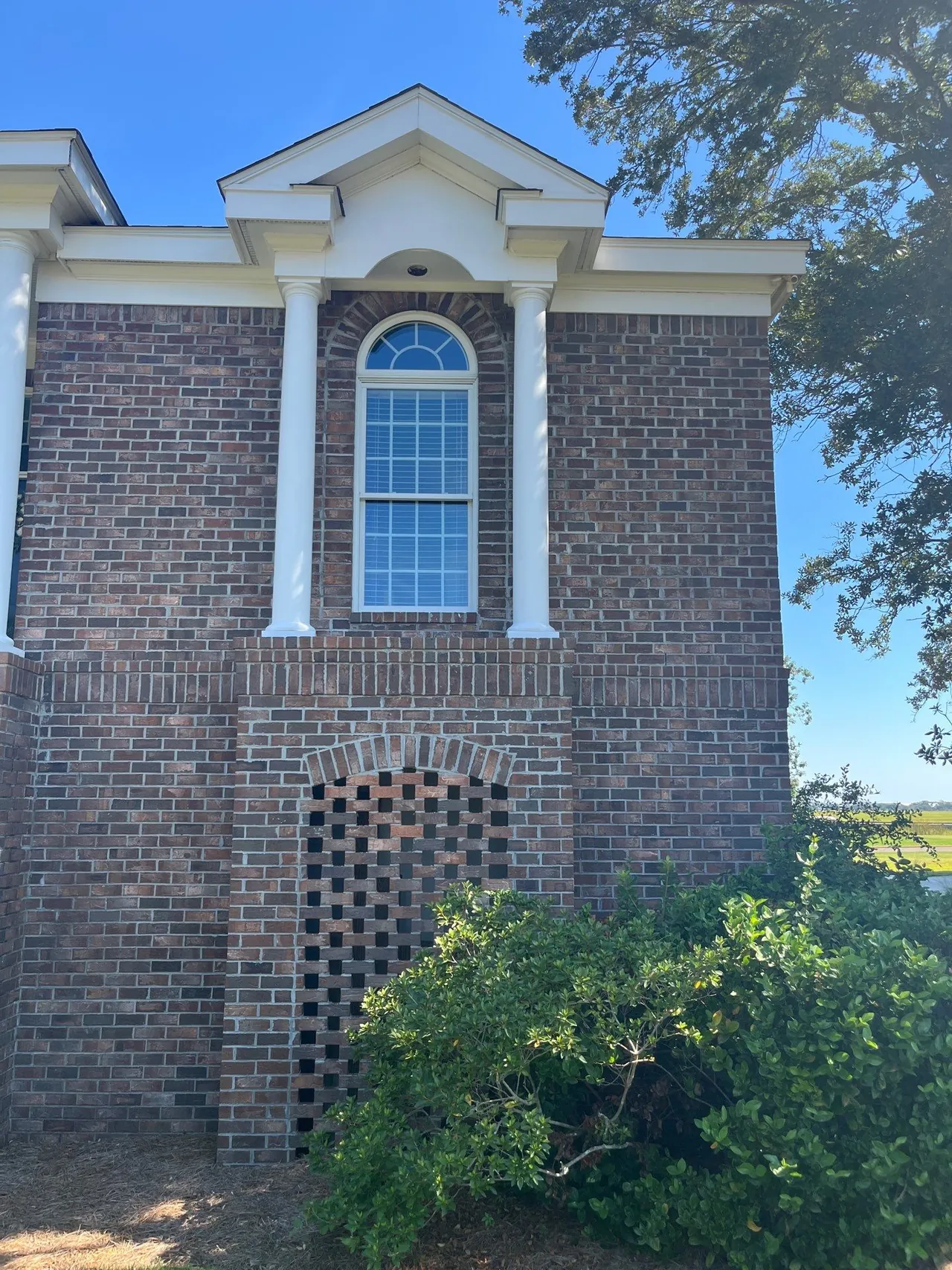 Original rectangular window and arched upper window framed by brick and white columns in Pawleys Island